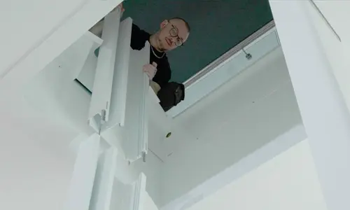A technician holding self supporting rails for a Luma through the floor lift installation.
