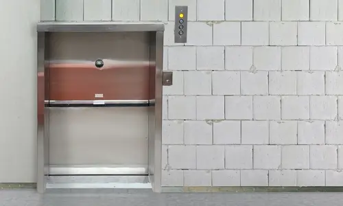 A stainless steel material lift installed in a commercial setting.
