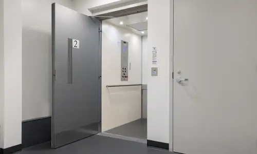 A white and gray Prolift vertical platform lift with a gray open door.