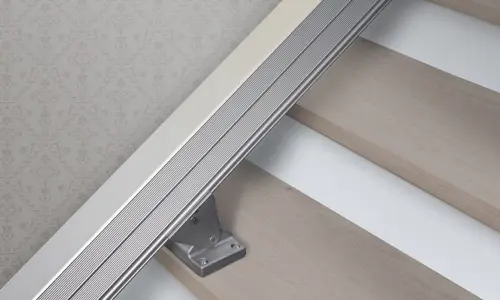 Stairlift rail mounted along the staircase, showing a slim metal track supported by a bracket fixed to the stair treads.