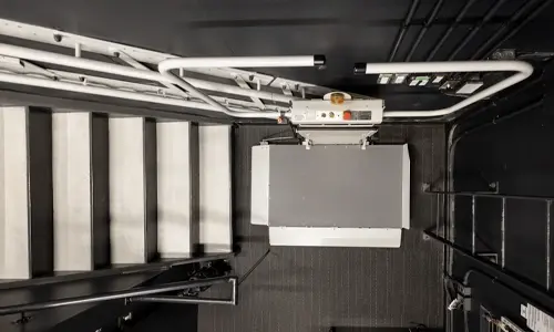 Aerial view of a inclined platform lift at the bottom landing of a staircase.