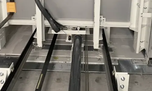 Lower part of elevator hoistway featuring guide tracks and mechanical assembly.