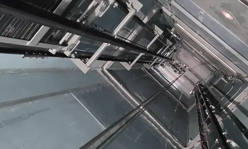 Interior view of a commercial material lift shaft showing guide rails, lift carriage framework, and mechanical components used for transporting goods between floors.