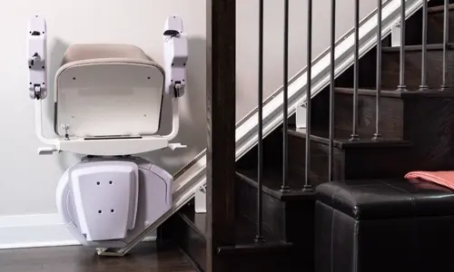 Folded straight stair lift mounted along a staircase railing in a modern home.