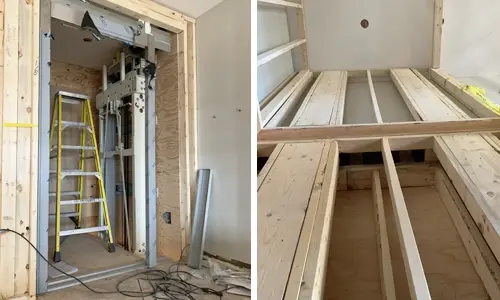 Elevator hoistway under construction, showing an unfinished shaft with exposed framing and an installed lift framework on one side, alongside raw wood joists and uncompleted walls before full elevator installation.