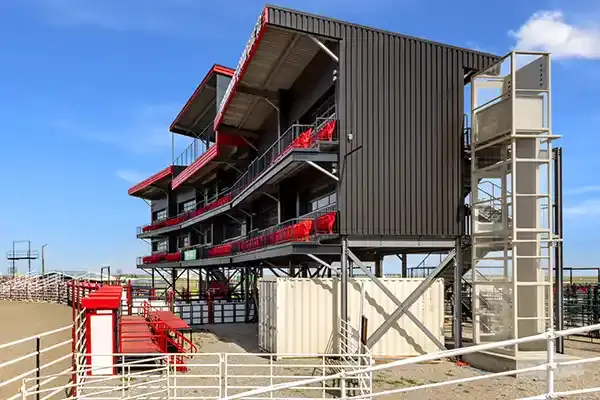 Modular multi‑level industrial building with exterior vertical platform lift tower providing accessibility to elevated work levels.
