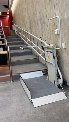 An inclined platform lift installed along the wall of a lecture hall.