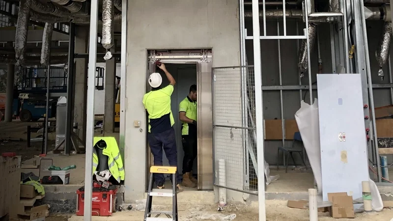 Elevator technicians at a unfinished job site working on an elevator install.