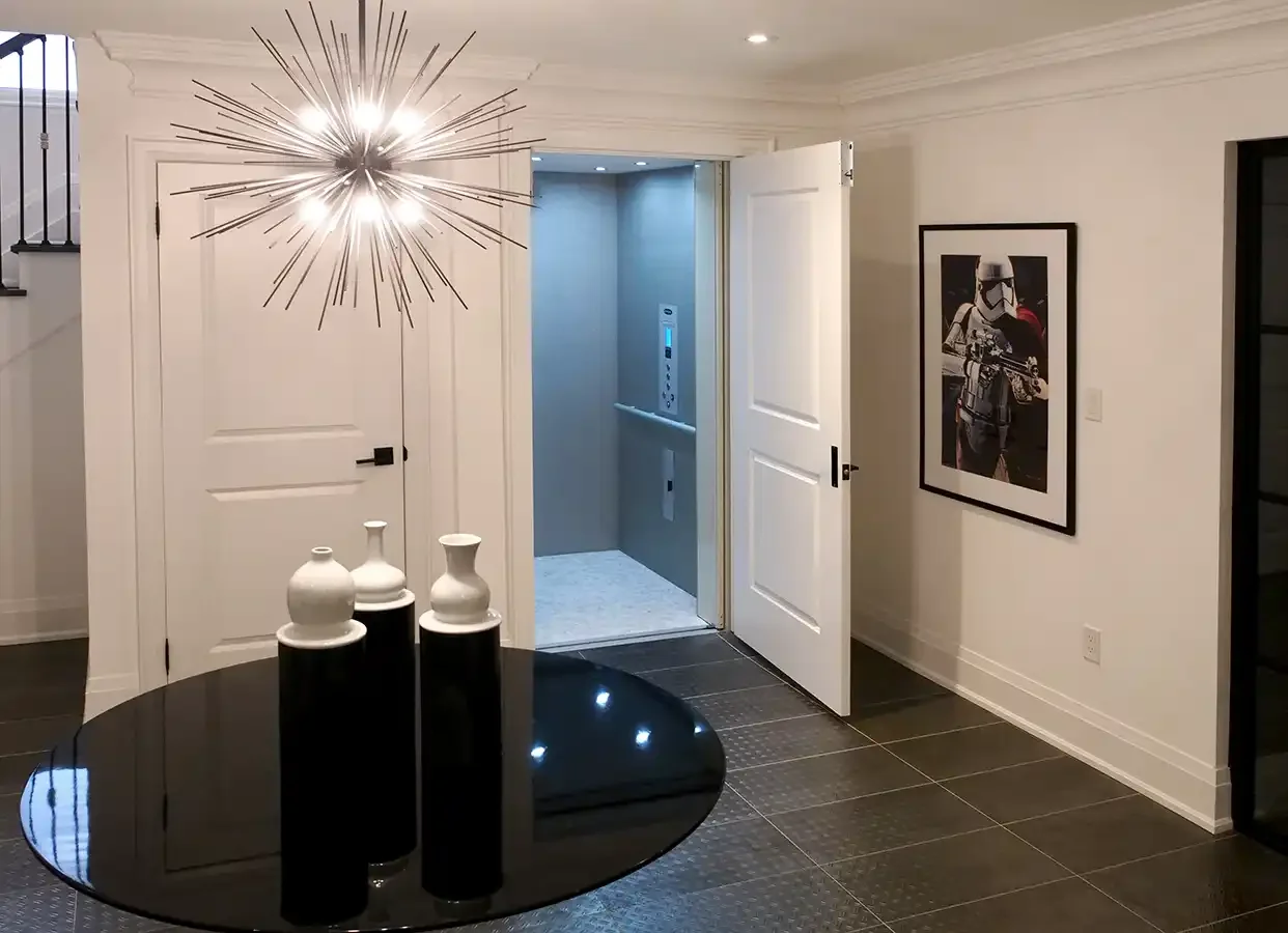 Modern interior with a starburst chandelier, open residential elevator, and minimalist decor.