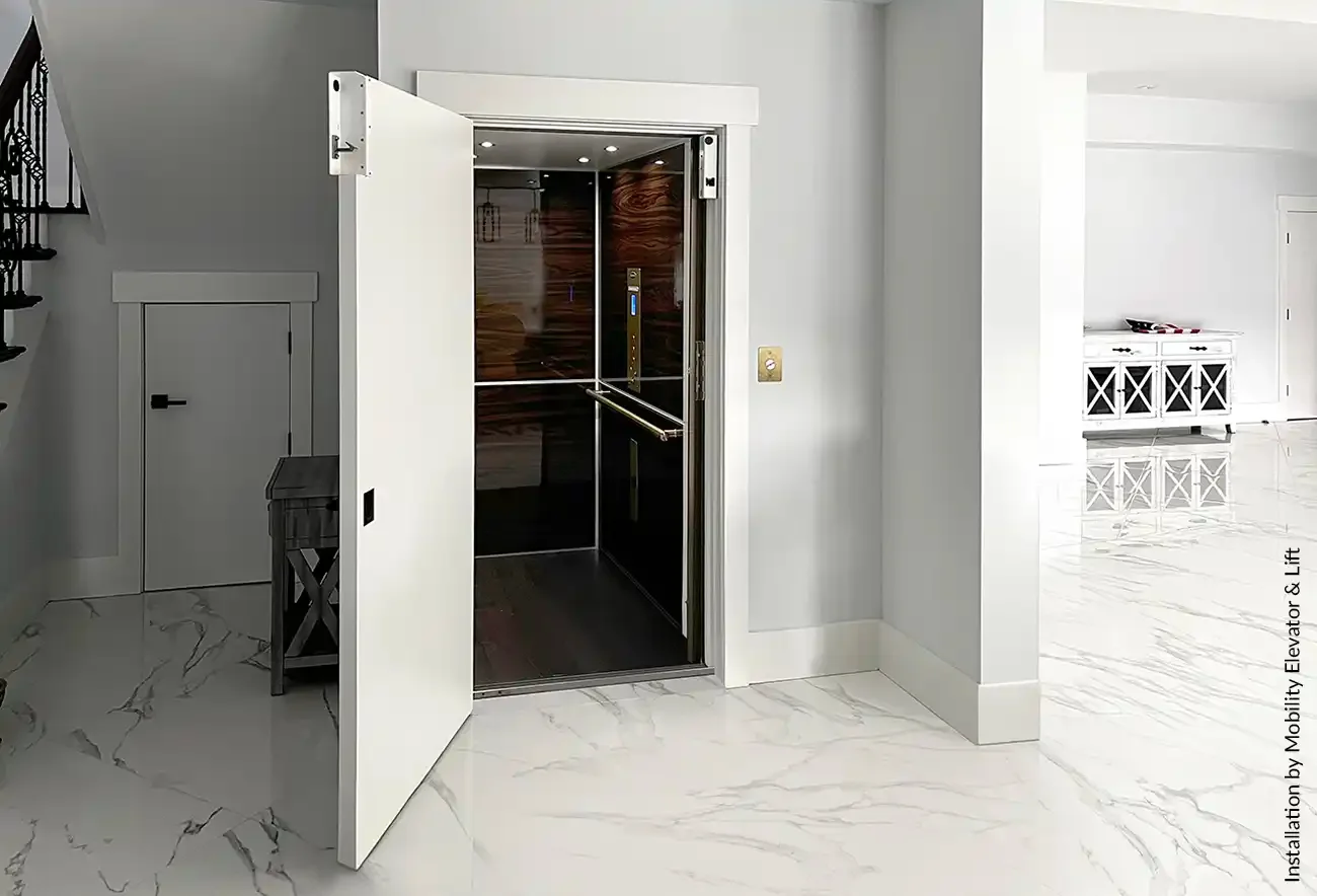 Modern home interior with an open residential elevator, wood-paneled cabin, and marble flooring