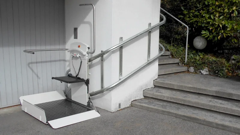 Inclined platform lift installed with custom made twin rails along an exterior stone staircase