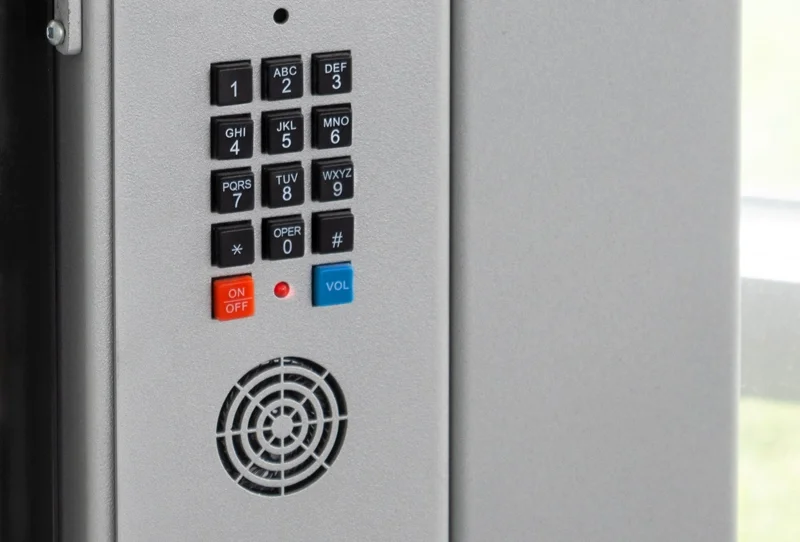 Elevator phone panel with a numeric keypad, emergency on/off button, volume button, and a speaker grille below.