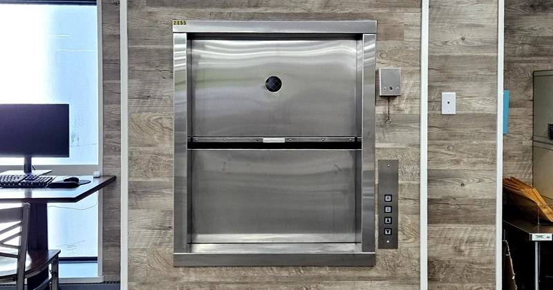 Office material lift with stainless steel dumbwaiter door installed in a modern workplace, designed for transporting documents, supplies, and equipment between floors.