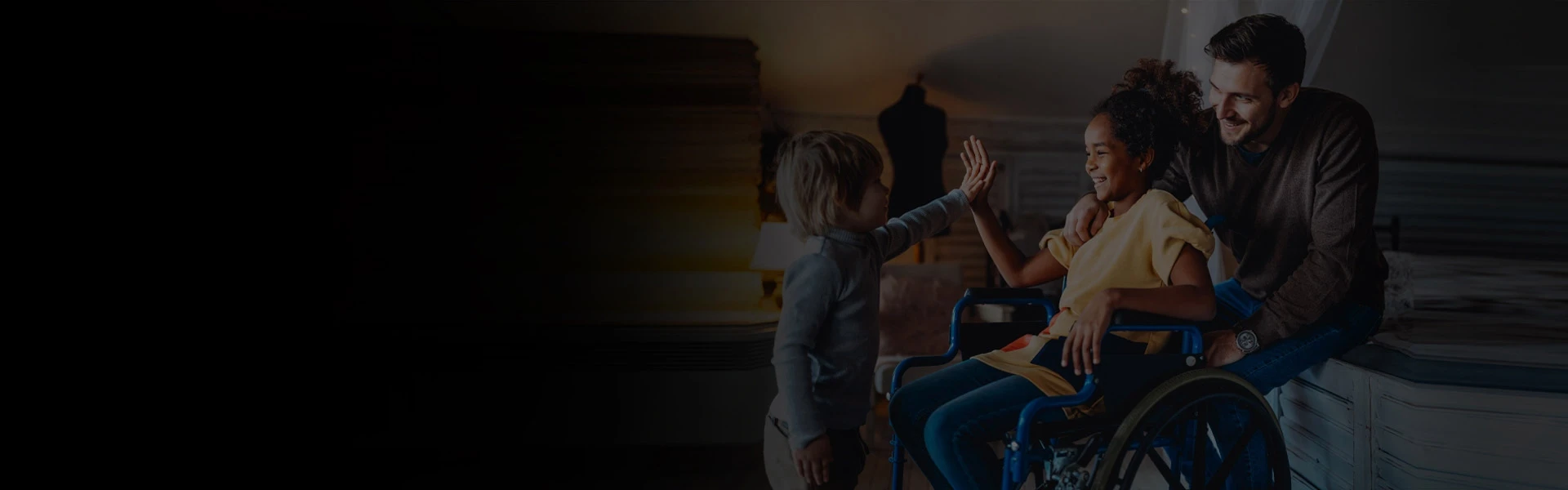 Child giving a high‑five to another child seated in a wheelchair while an adult offers support nearby.
