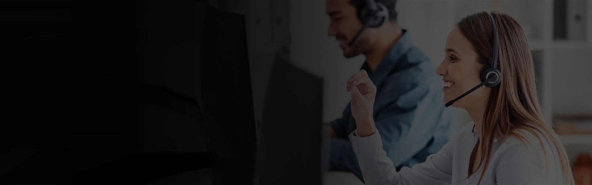Customer support representative wearing a headset working at a computer workstation in a modern office