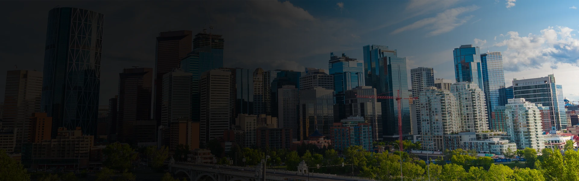 Calgary skyline with modern high-rise buildings and the Bow Tower under a dramatic sky