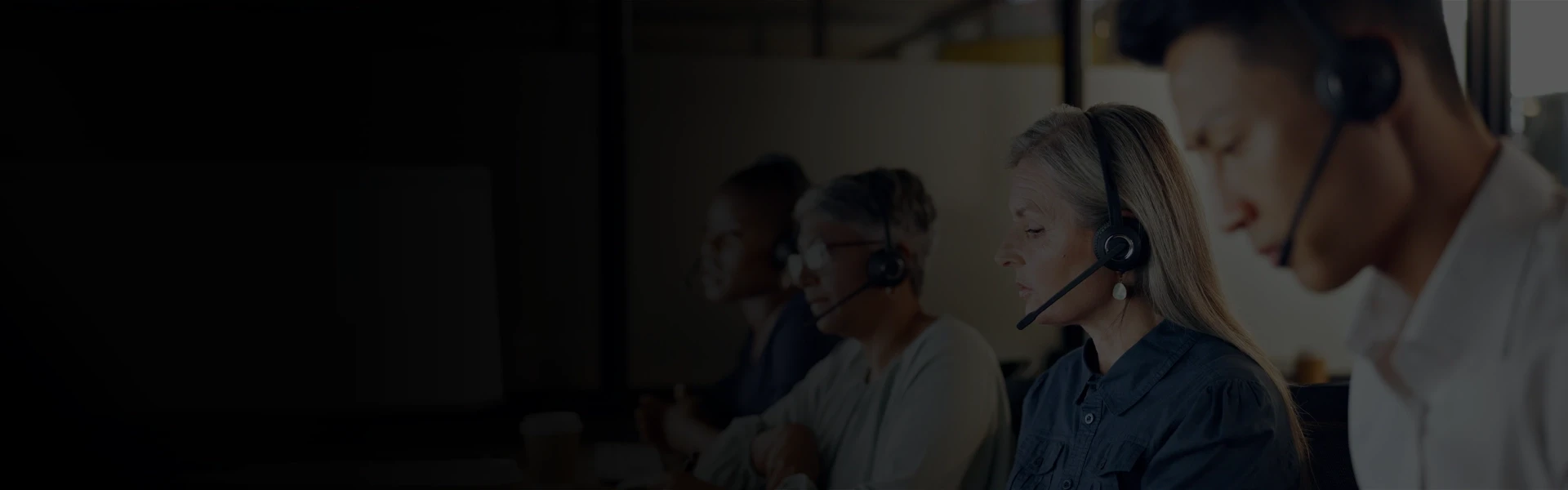 Customer support representatives wearing headsets working at computer workstations in a modern office