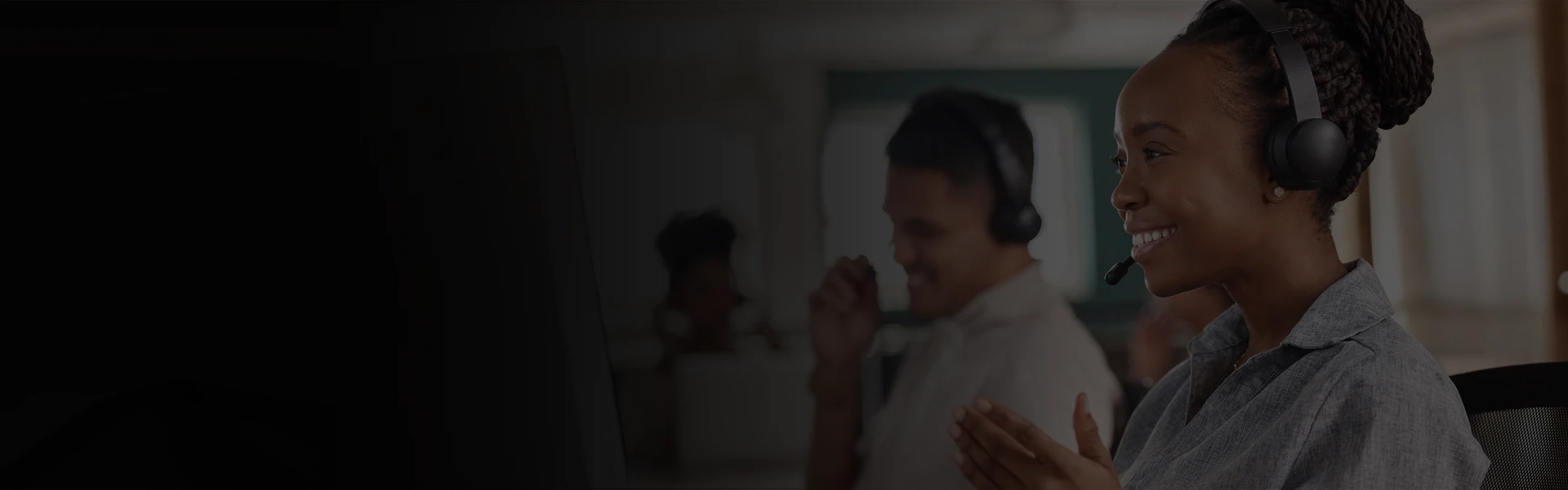 Customer support representative wearing a headset working at a computer station in a modern office