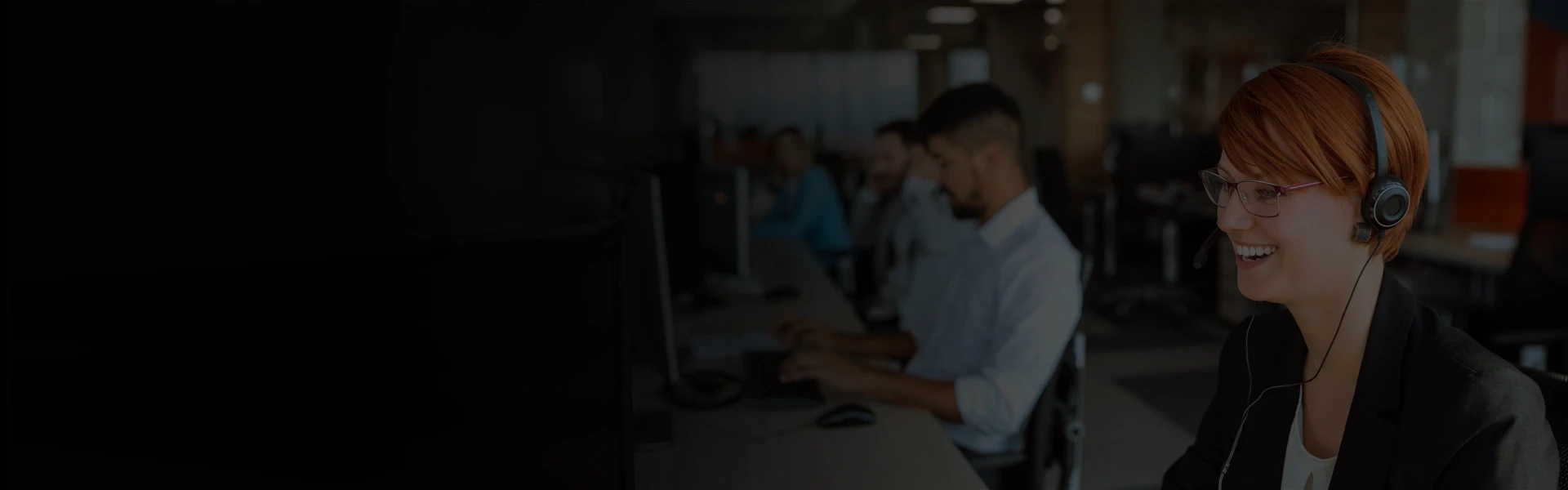Customer support representatives wearing headsets working at computer stations in a modern office