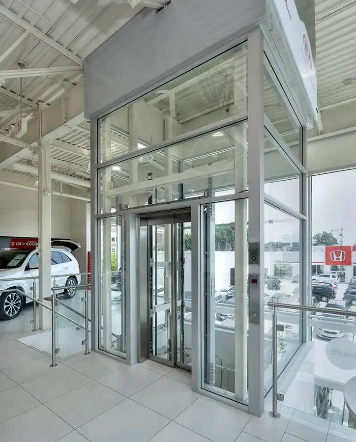 Glass residential elevator with aluminum framing in a bright commercial showroom
