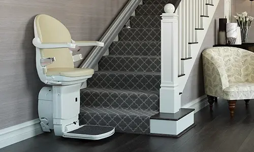 A Handicare 1000 straight stairlift installed along a diamond patterned carpet staircase.