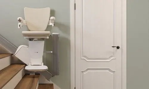 A Handicare 1100 showcasing a foldable track next to a white door.