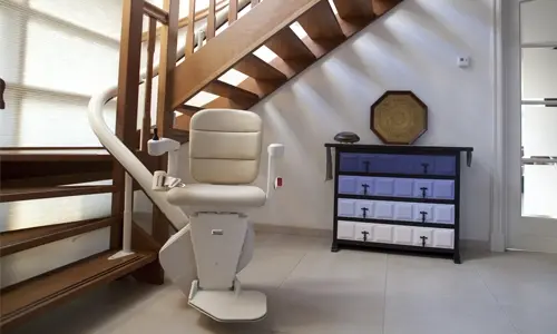 A Handicare Freecurve curved stairlift installed along an open staircase next to a blue graddient dresser.