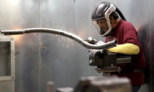 Worker grinding down a custom bend in a curved stairlift rail.