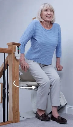 Elderly woman showcasing the power option of the swivel seat for ease of access at the top landing of staircase.